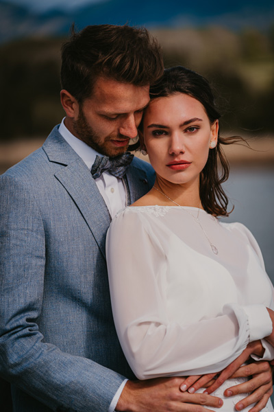 Nahaufnahme von nachdenklichem Brautpaar in zärtlicher Umarmung auf der Bergsee-Hochzeit